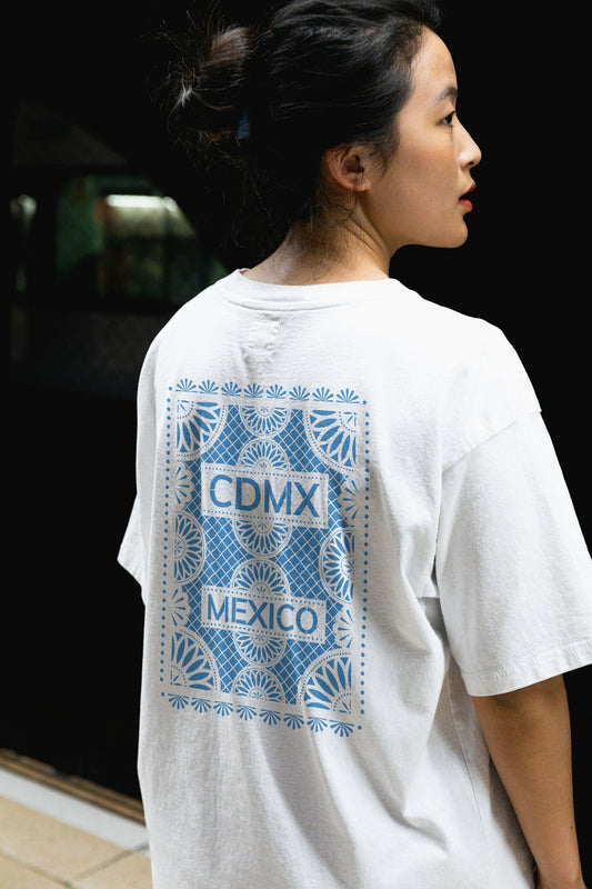 Back view of Unisex White Crewneck T-Shirt featuring blue Papel Picado CDMX Mexico design on woman model